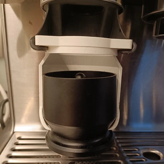 Black coffee cup being filled with coffee from a coffee machine.