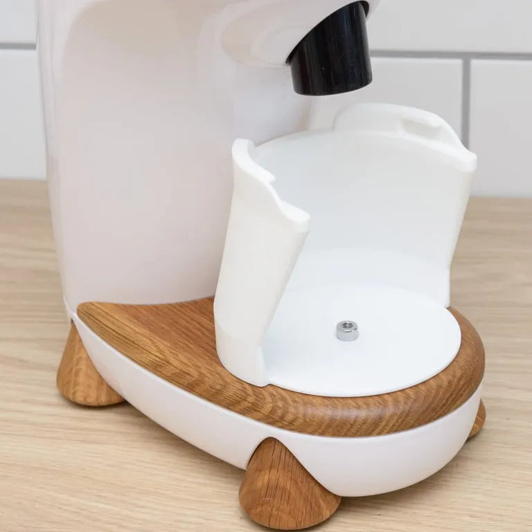 White coffee maker with wooden base on a wooden surface